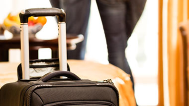 suitcase in hotel room with couple in background